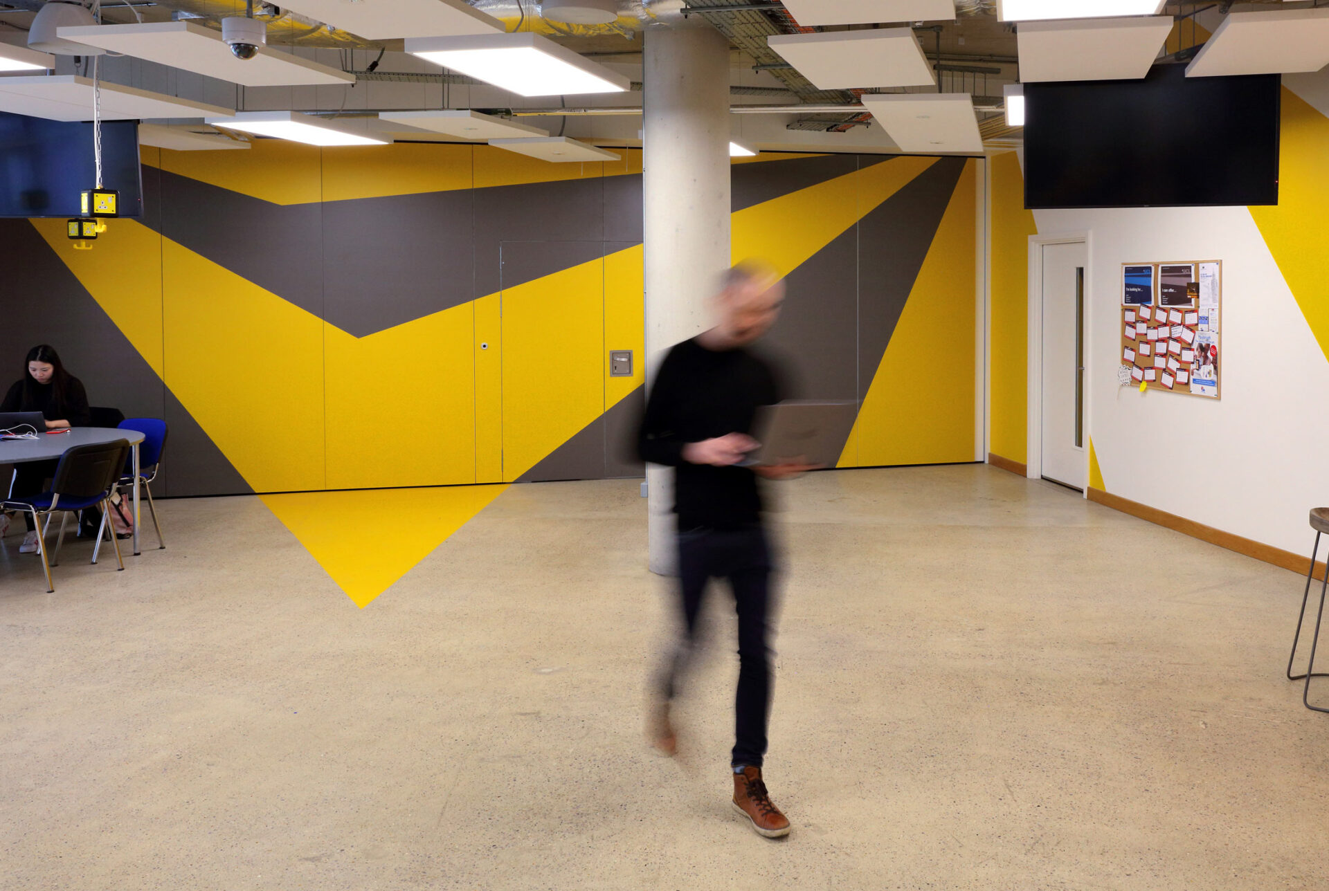 UCL Innovation & Enterprise branded decal in situ in their working environment. Yellow and grey two colour pattern symbolising energy and action